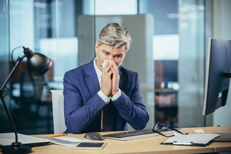 The boss business man works in the office, has a strong allergy to sneezes and runny noseの写真素材