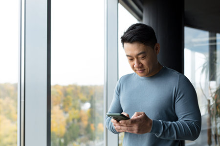 Asian businessman uses the phone in the office, portrait of a man looking at the phone screen,...