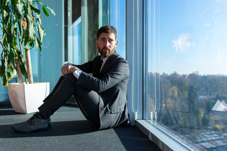 Depressed man sitting on office floor, employee disappointed and fired