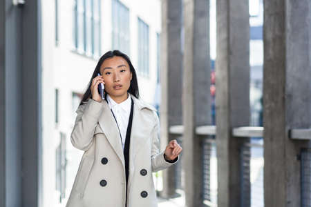 Beautiful and happy asian woman talking on the phone, Chinese student walks in the breakの写真素材