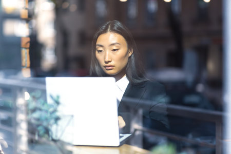 Beautiful female student working at computers, Asian woman in cafe look through word window