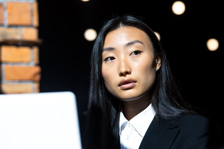 Close-up photo portrait of Asian business woman looking at laptop screen, working remotelyの写真素材