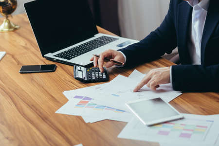 Close-up photo, businessman accountant's hand counts on a calculator, man sitting at a table paperworkの写真素材