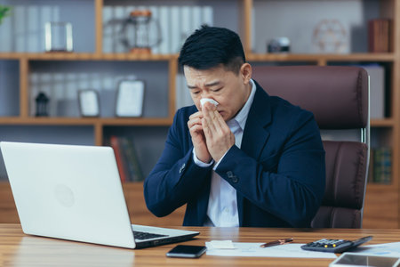 Businessman working in the office, sick Asian has a cold and flu, runny nose from allergiesの写真素材