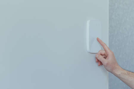 Businessman enters finger password lock code on alarm panel, on white wall, rear view of man with beardの写真素材