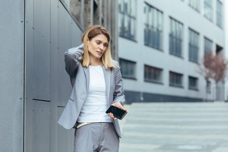 Woman near the office has severe back and neck pain, fatigue and depression of a business woman from...