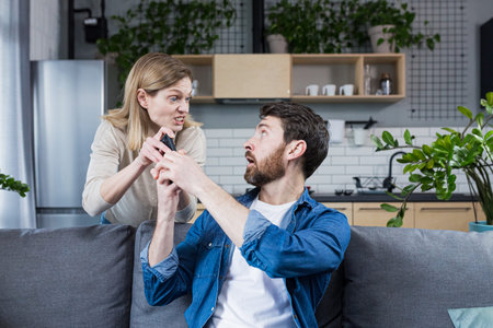 Conflict in the family. An angry, annoyed woman's wife takes the phone from the man who is sitting...