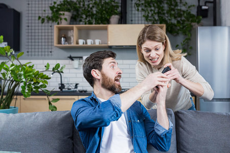 Conflict in the family. An angry, annoyed woman's wife takes the phone from the man who is sitting...