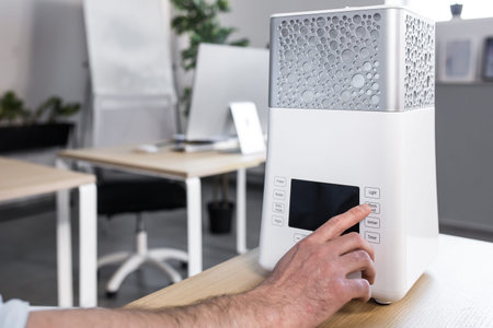 close up photo. A man's hand that includes a desktop humidifier or air conditioner on the desktop...