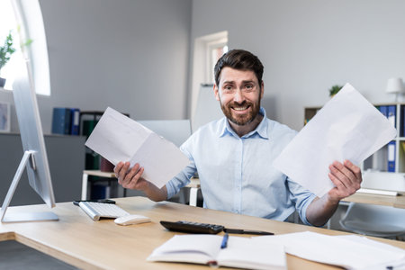 Happy businessman at paper work, examining financial documents, man at work working in the office
