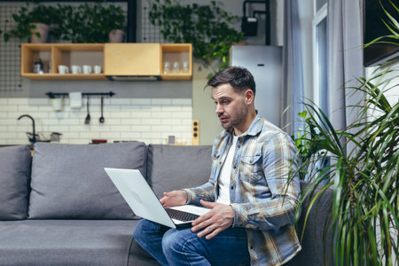 Young man working from home with laptop. Talks on video call. Sitting on the couch.の写真素材