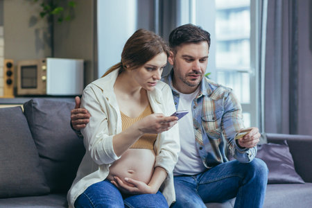 Worry. Young family, pregnant woman and husband holding credit card and phone. Check, do not...
