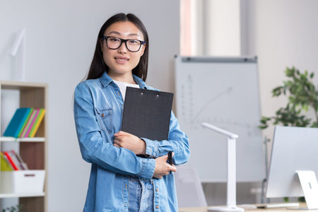 Young beautiful Asian female teacher looking at the camera and smiling, portrait of a woman in the...