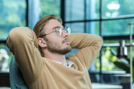 A close-up photo of a man resting in the office, a businessman with his hands behind his head with his eyes closed is dreaming, a close-up photoの写真素材