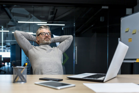 Senior gray haired man resting in office on chair with hands behind head, businessman boss working...