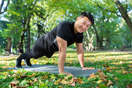Portrait of happy male athlete, Asian looking at camera and smiling doing physical exercises,...