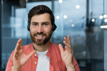 Close-up portrait of mature tech support worker looking at camera and smiling man talking on video call customer helpline customer service online business man working inside modern office building.の写真素材