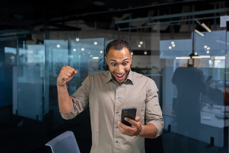 Businessman is happy to celebrate victory and success, Hispanic man inside the office holds a...