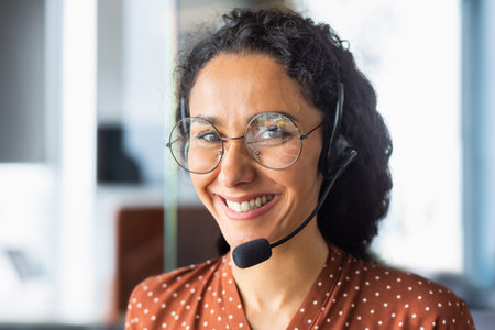 Close up portrait of latin american woman inside modern office with headset for video call, woman...