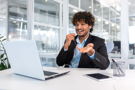 Young successful hispanic businessman boss talking on video call remotely with colleagues and...