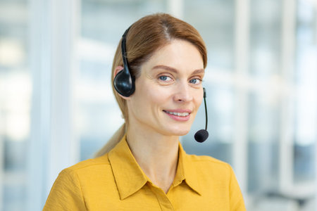 Portrait of mature female customer service worker, mature business woman with video call headset...