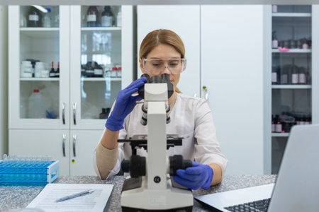 Young woman scientist. a chemist works in a clinic laboratory, sits at a table in a coat and goggles...