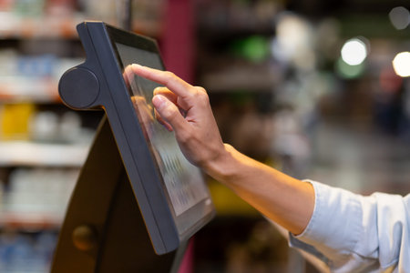 Close-up photo of a womans hand in a supermarket inside using a self-service scale weighing...