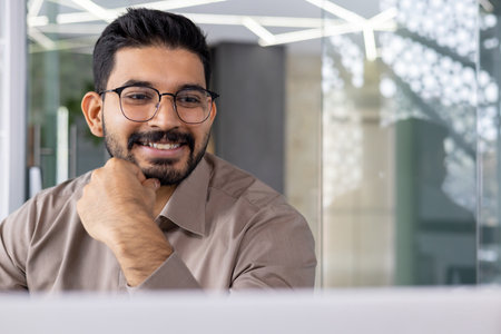 Businessman close up inside office at workplace, man in glasses and shirt smiling reading email using laptop, employee satisfied with financial report results, dreamy and happy.の写真素材