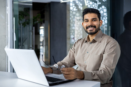 Portrait of accountant financier at workplace, businessman with laptop smiling and looking at camera...