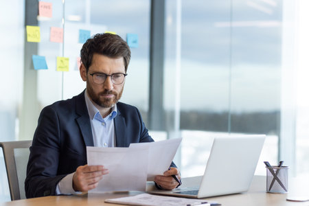 Serious thinking businessman behind paper work, mature experienced boss working with reports and...