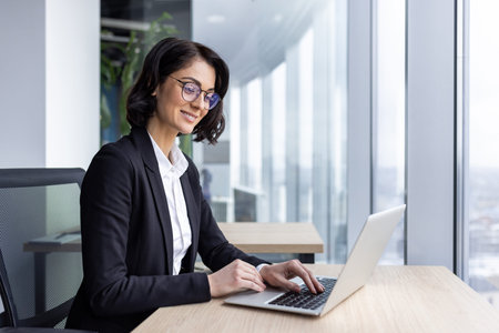 Businesswoman mature boss at workplace inside office, woman in business suit working contentedly...