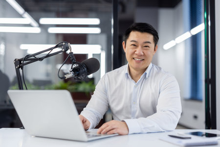 Portrait business coach, male mentor recording audio podcast in studio, businessman working with...