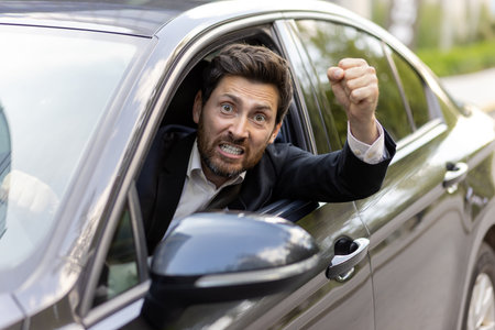 An angry and irritated young man in a business suit looks out of the car window. He is behind the...
