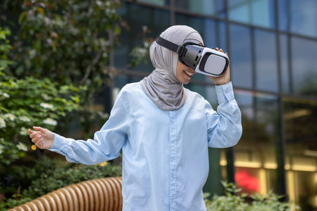 Smiling Muslim lady in hijab using virtual reality headset outside, experiencing modern technology...