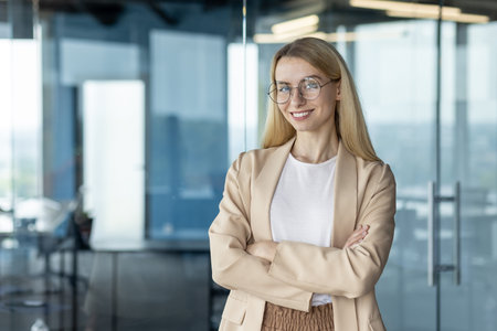 A confident businesswoman with blonde hair and glasses poses arms crossed in a stylish modern...
