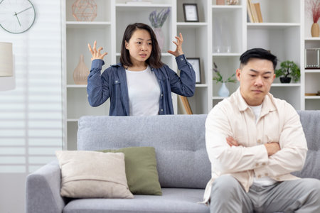 Young couple having an argument in their living room, showcasing stress and relationship issues.の写真素材