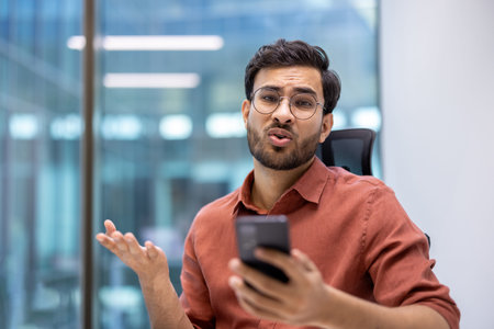 Office worker expressing frustration during phone call in modern office. Professional being annoyed....