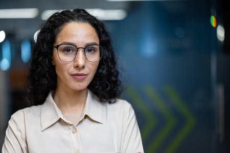 Portrait of confident businesswoman with glasses standing in modern office setting. Professional...