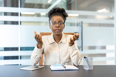 Confident businesswoman in an office, engaged in a video call, looking at camera, communicating...
