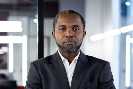 Portrait of confident businessman in formal suit standing in modern office, expressing leadership...
