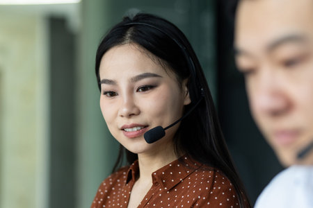 Asian business team engaged in professional work environment using headsets for effective...