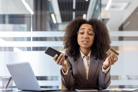 Financial problems with a bank account. Portrait of an upset and disappointed young business woman in the office, holding the phone and waving her hands at the camera.の写真素材