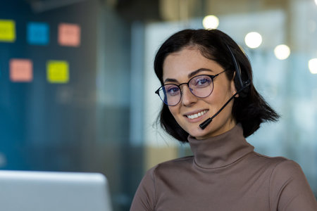 Confident customer service representative with headset and glasses smiling at camera. Engaged in conversation at work with positive demeanor. Represents communication, professionalism, and supportの写真素材