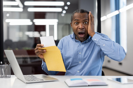 African American mature businessman expresses surprise and disbelief while opening unexpected mail....