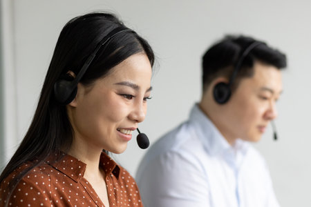 Customer service representatives wearing headsets engaged in communication, showcasing dedication in call center setting. Office workers demonstrate teamwork, problem-solving skillsの写真素材