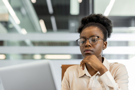 Young professional with glasses focused on work. Shows determination and concentration in modern office. Corporate setting highlights career and ambition, capturing essence of technology-driven .の写真素材