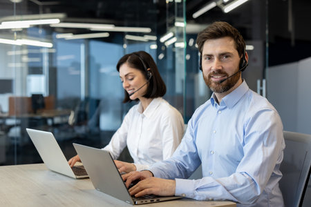 Customer service representatives using headsets and laptops in office. Focused on customer support, teamwork, and professionalism. Showcasing modern workspace and effective communication skills.の写真素材