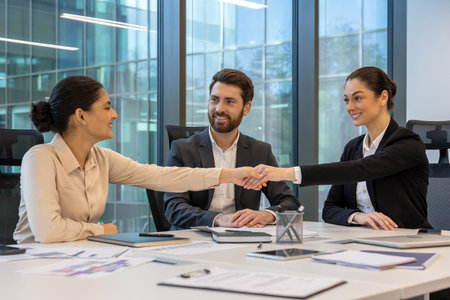 Business professionals in office shaking hands symbolizing cooperation, teamwork, successful...