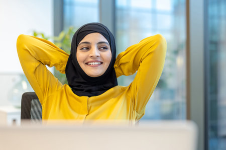 Successful woman completed work, businesswoman in hijab well done put her hands behind her head...