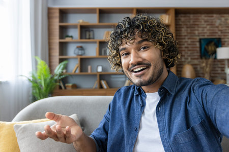 A cheerful man takes a selfie, capturing a moment of happiness in a cozy setting. The casual...